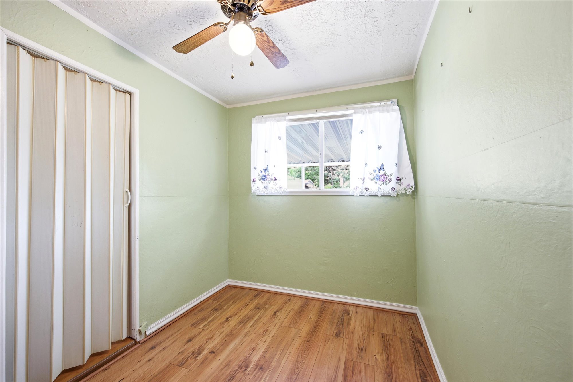 Interior room featuring wood-finish flooring, light green walls, and white trim