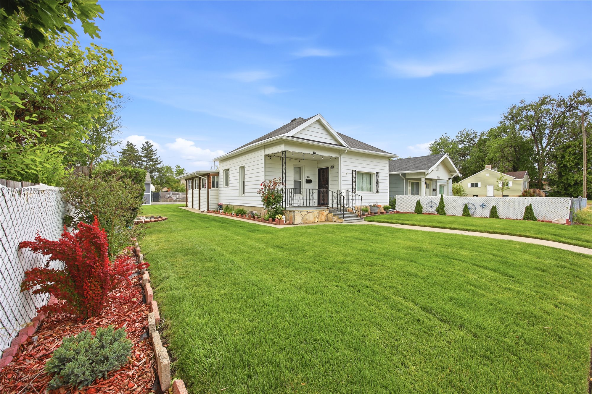 White siding residence with a covered front porch featuring wrought iron railings