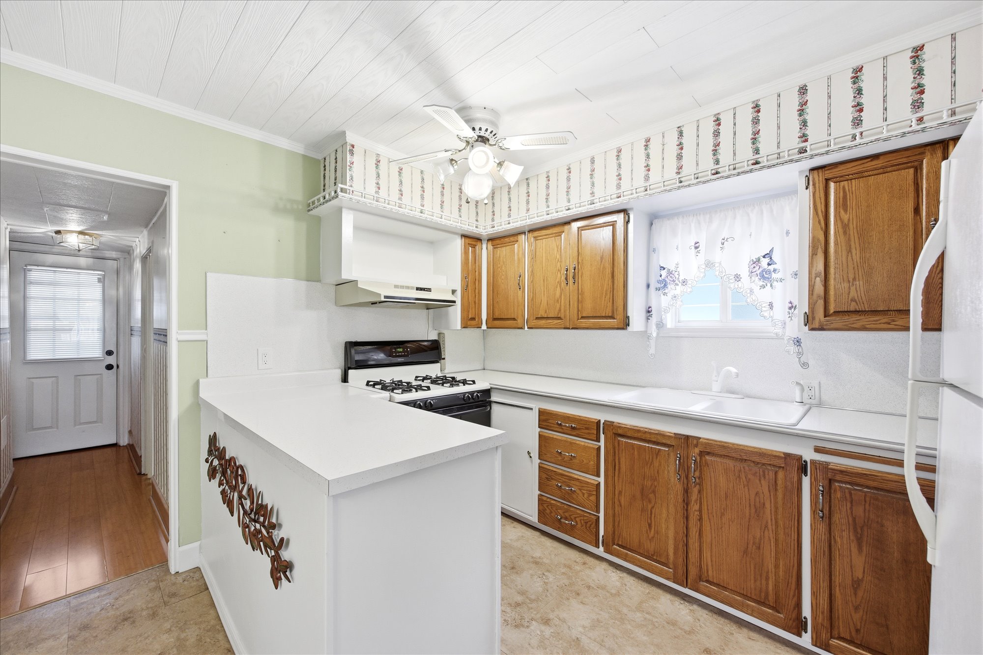Kitchen featuring wood cabinetry, white countertops, built-in gas range, dual basin sink, and a ceiling fan