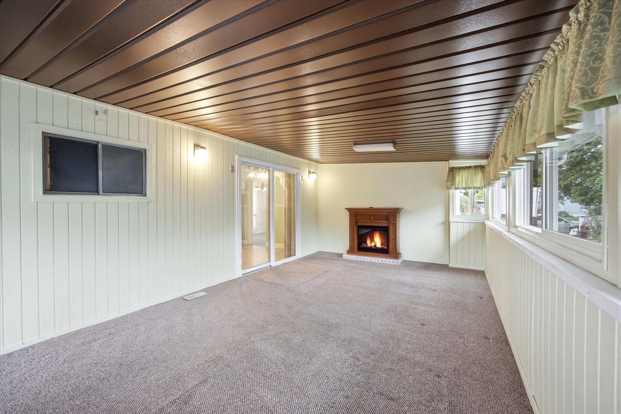 Sunroom featuring a wood-toned paneled ceiling, a wood-framed fireplace, full-length windows, and sliding glass doors