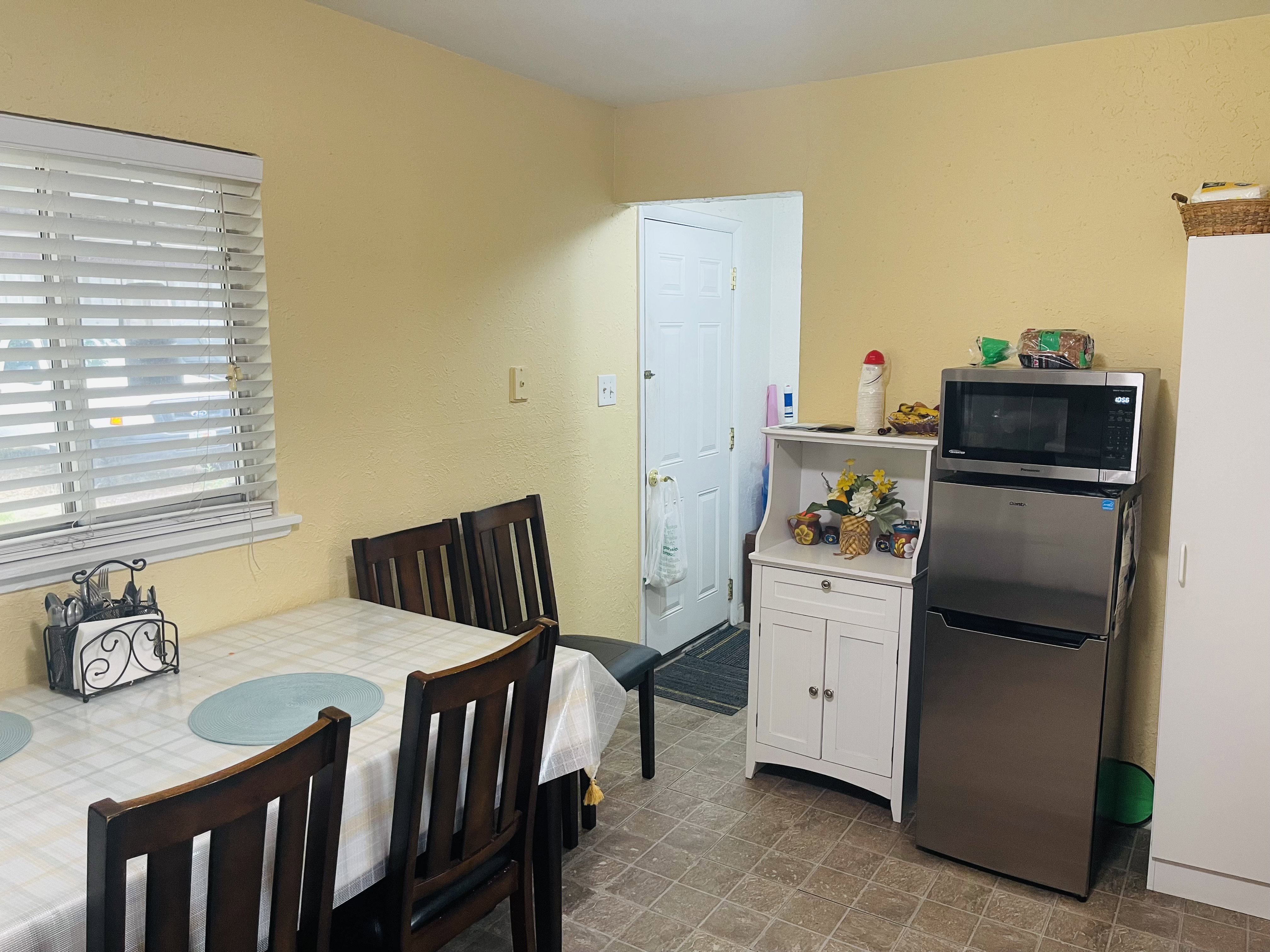 Dining area featuring a window with horizontal blinds, textured yellow walls, and patterned flooring