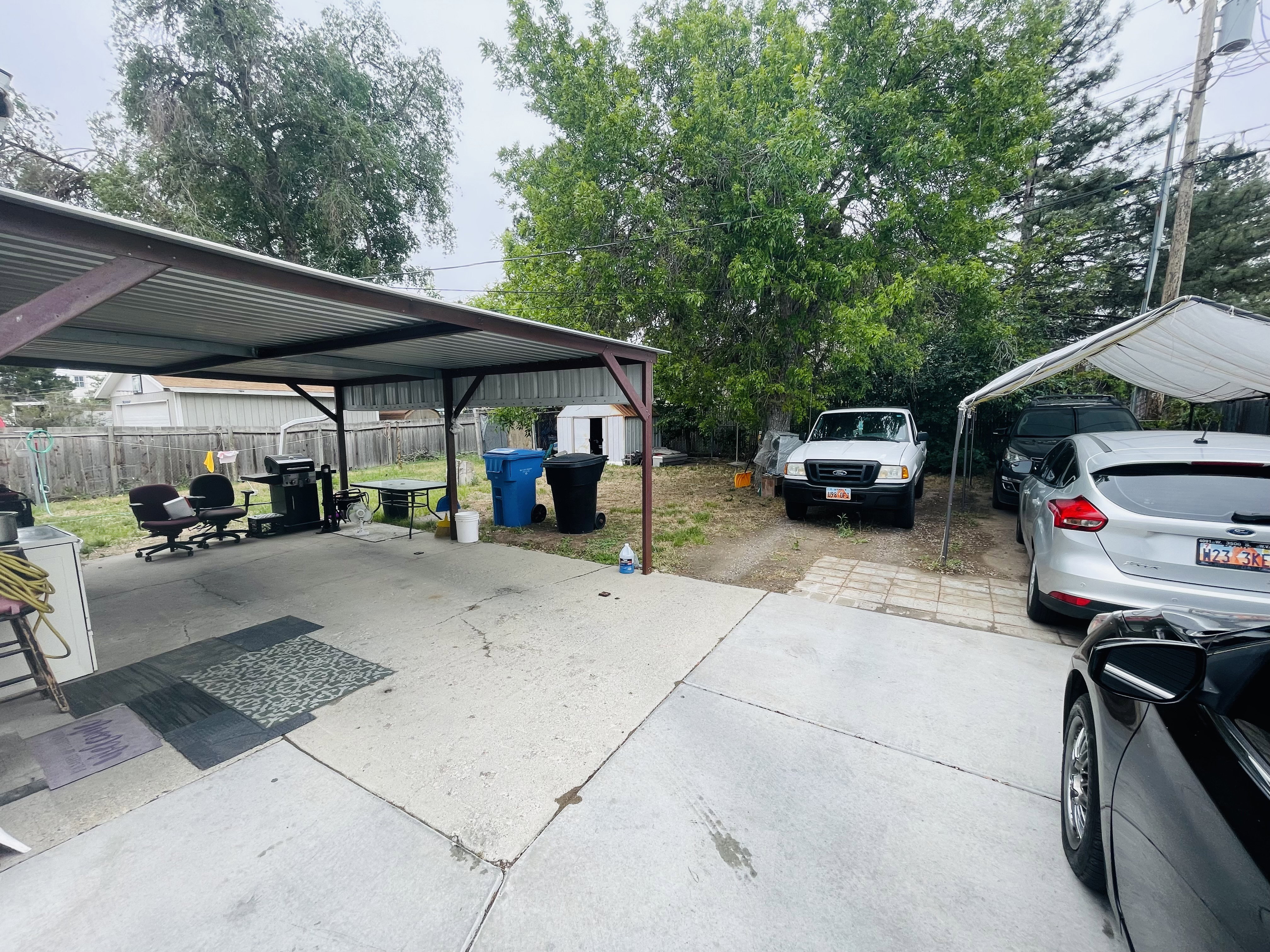 Concrete patio with a corrugated metal carport, offering covered outdoor space