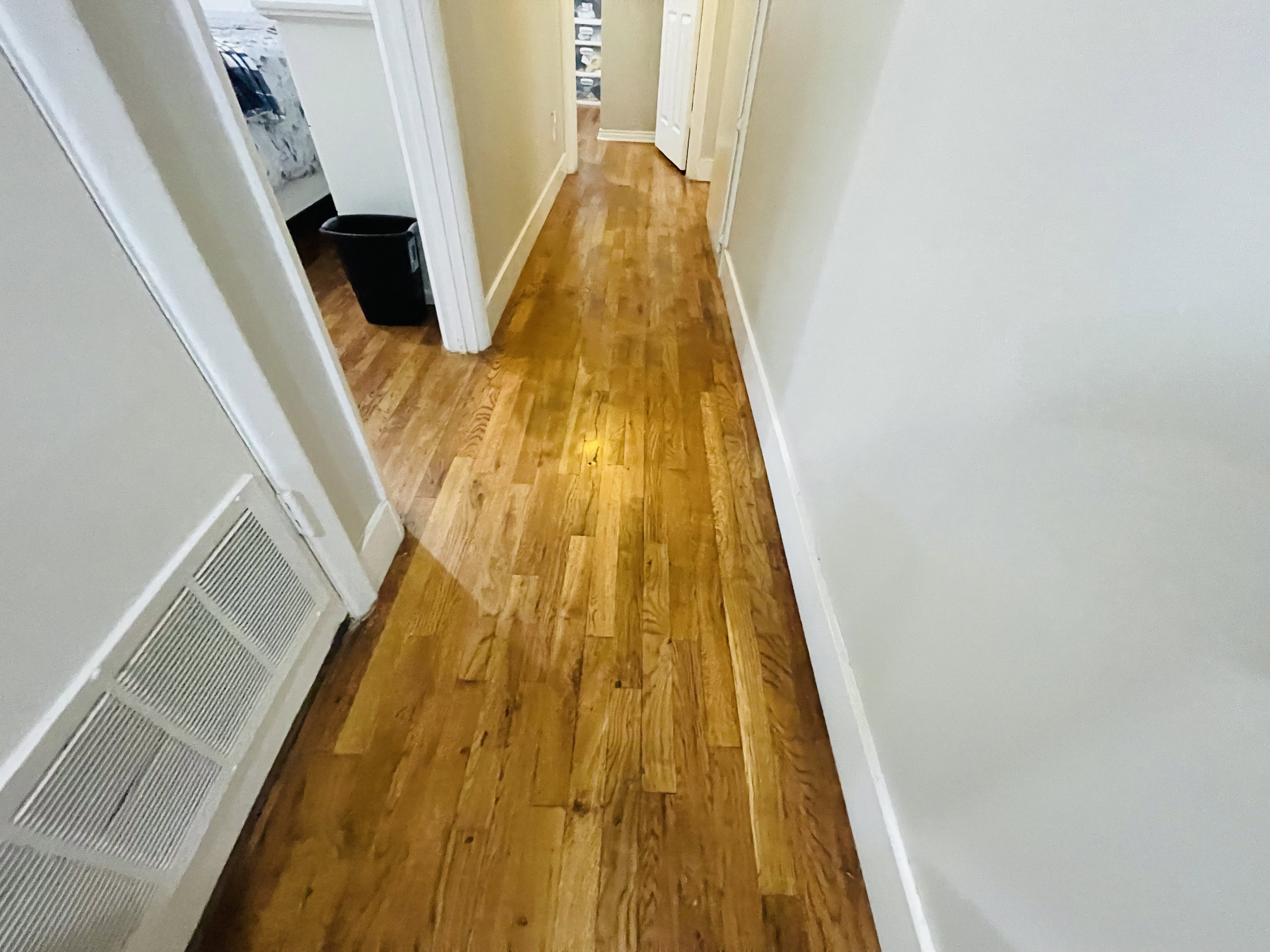 Hardwood flooring featured in a hallway with light-toned walls and white trim