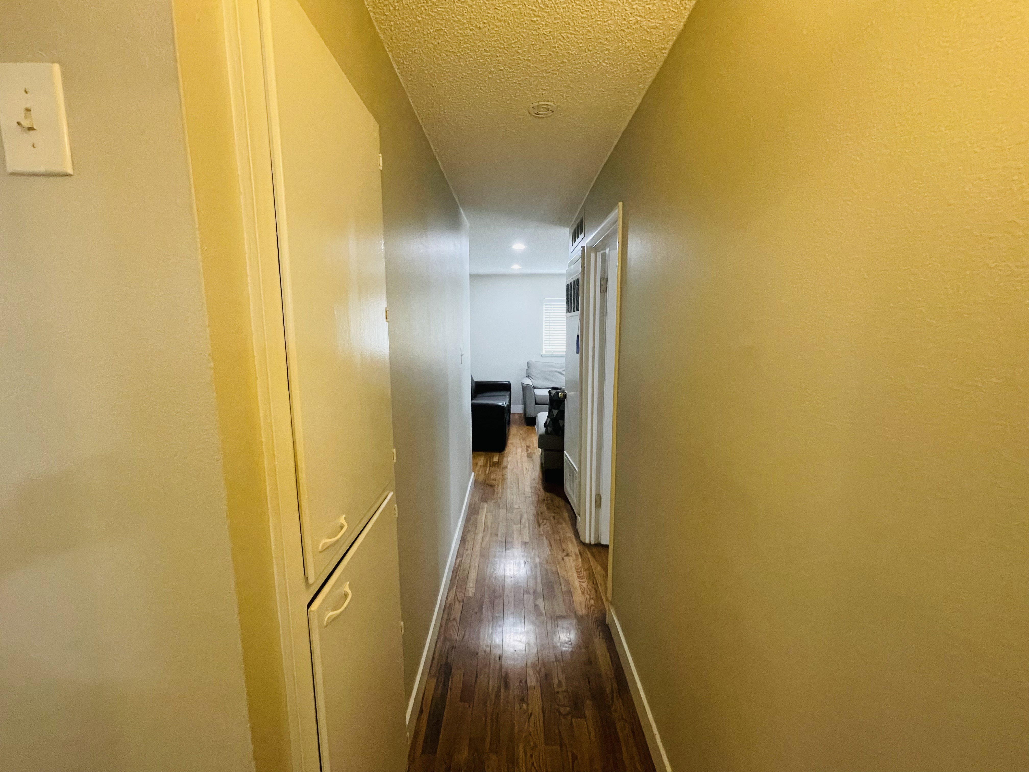 Hallway featuring wood-finish flooring, built-in cabinetry, and neutral wall tones