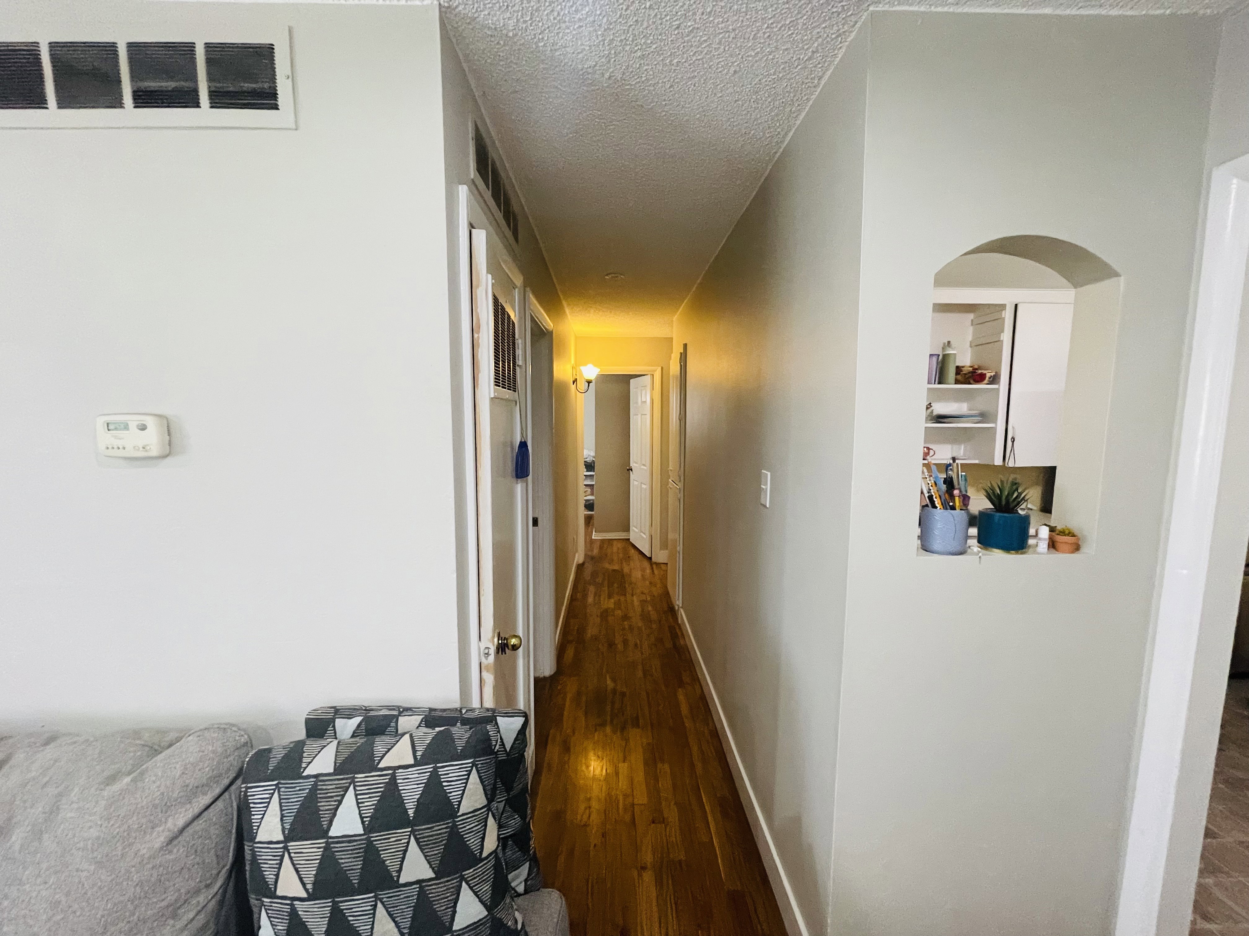 Hallway with wood-finish flooring, an arched wall cutout, and recessed lighting