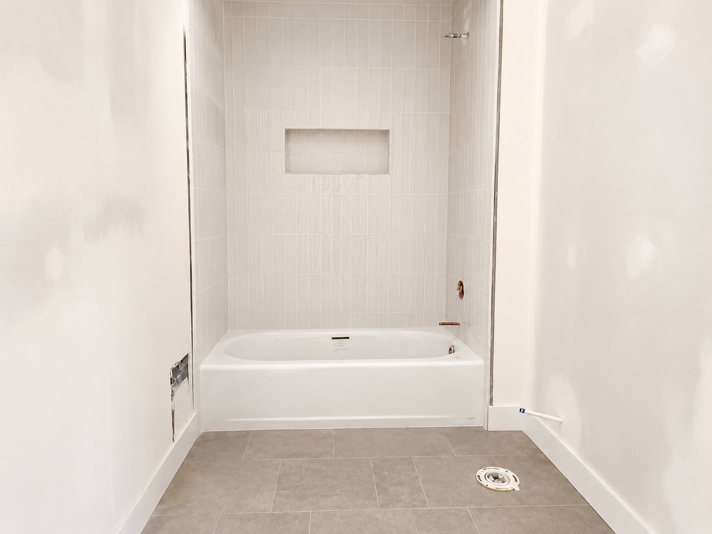 White tub and shower combination with light-toned rectangular tile surround