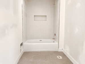 White tub and shower combination with light-toned rectangular tile surround