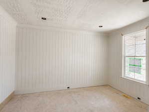 Room featuring vertical paneling, crown molding, and a single-hung window with a paneled apron