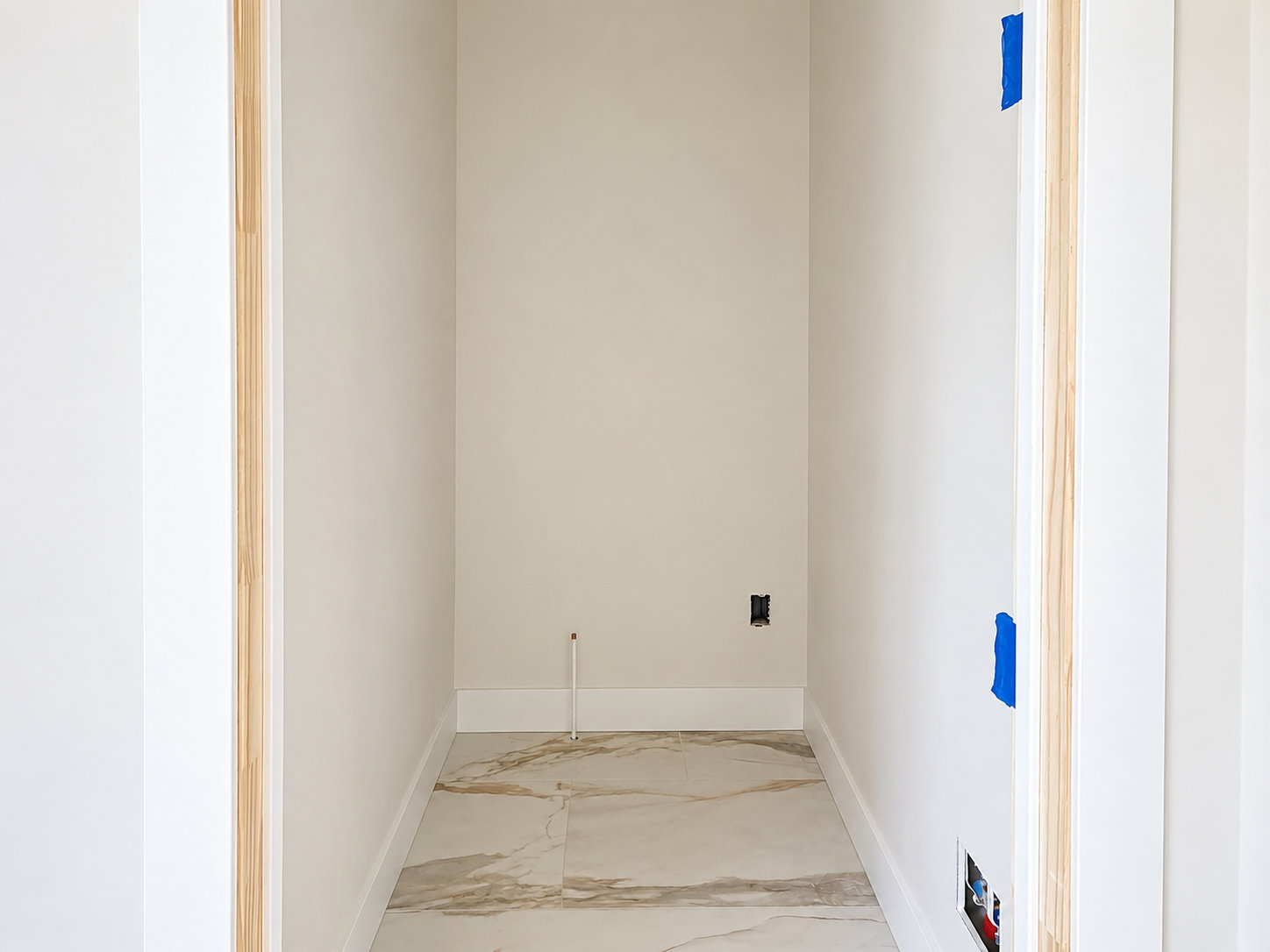 Alcove featuring large format stone-look tile flooring, light-toned walls, and white trim