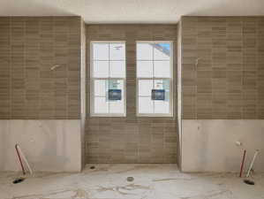 Spacious bathroom featuring two double-hung windows, horizontal subway tile accents, and marble-look floor tiles