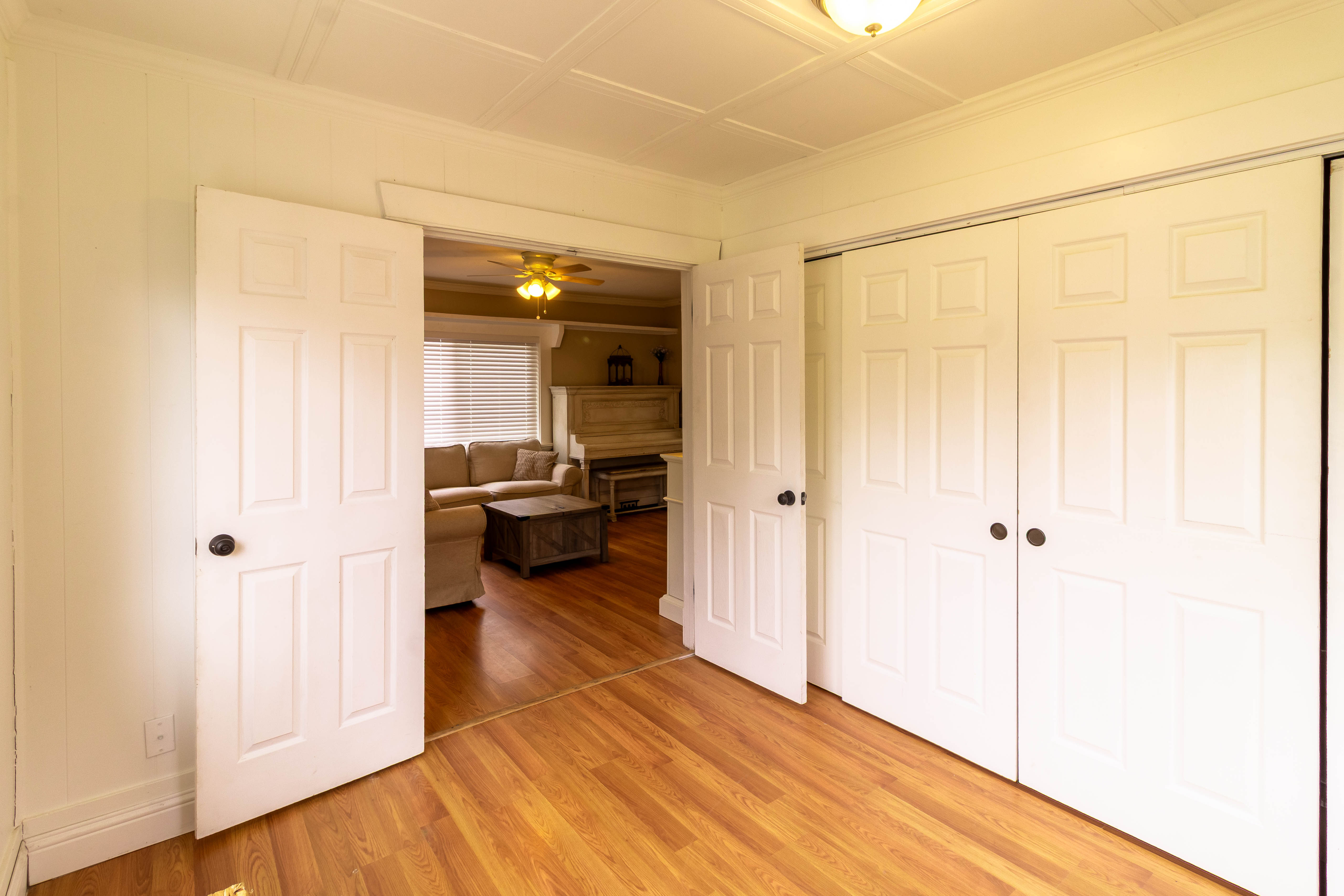 Interior space featuring wood-finish flooring, white paneled bifold closet doors, and a decorative ceiling light fixture