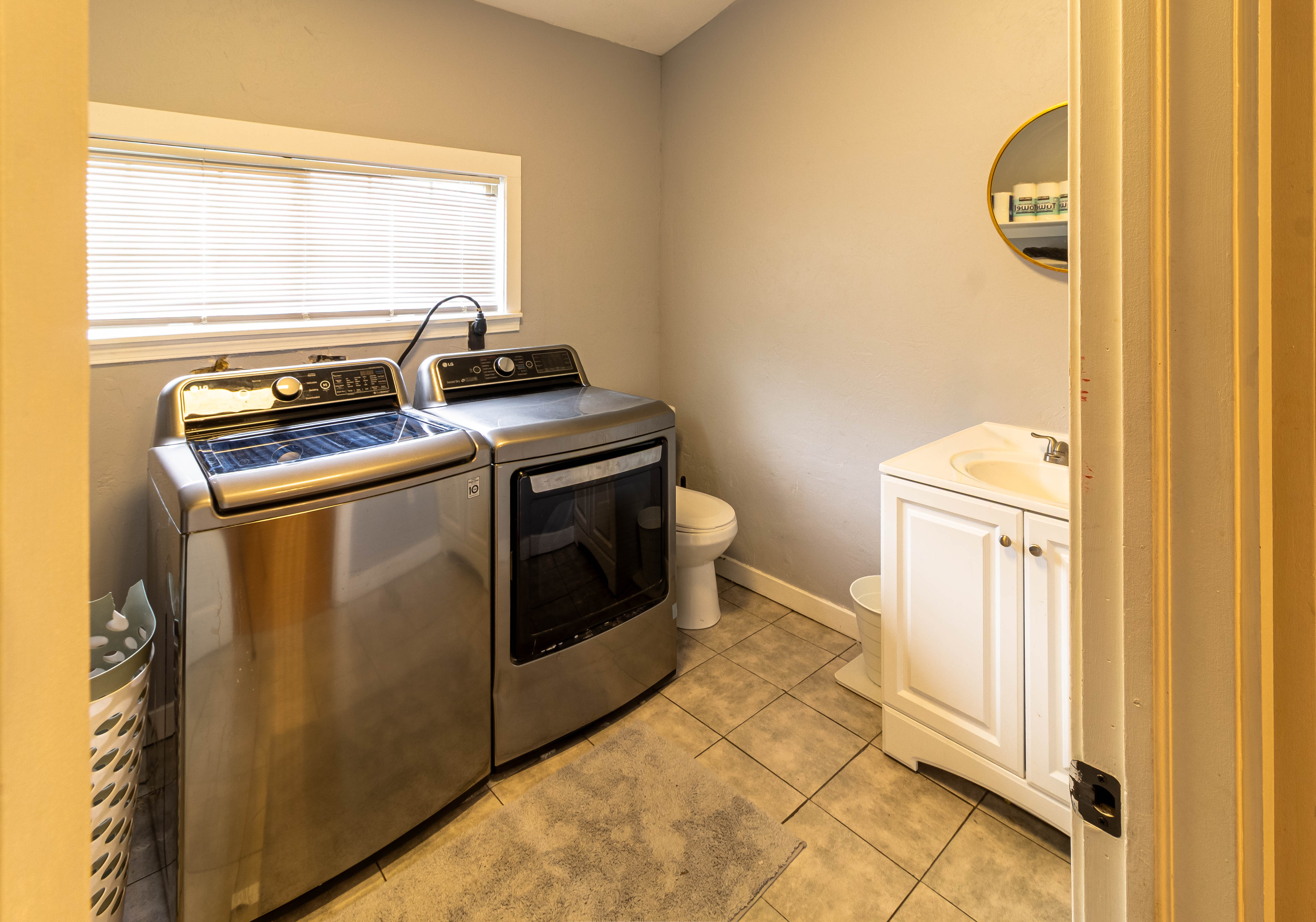 Laundry area with tile flooring, a window offering natural light, and a white vanity with an integrated sink