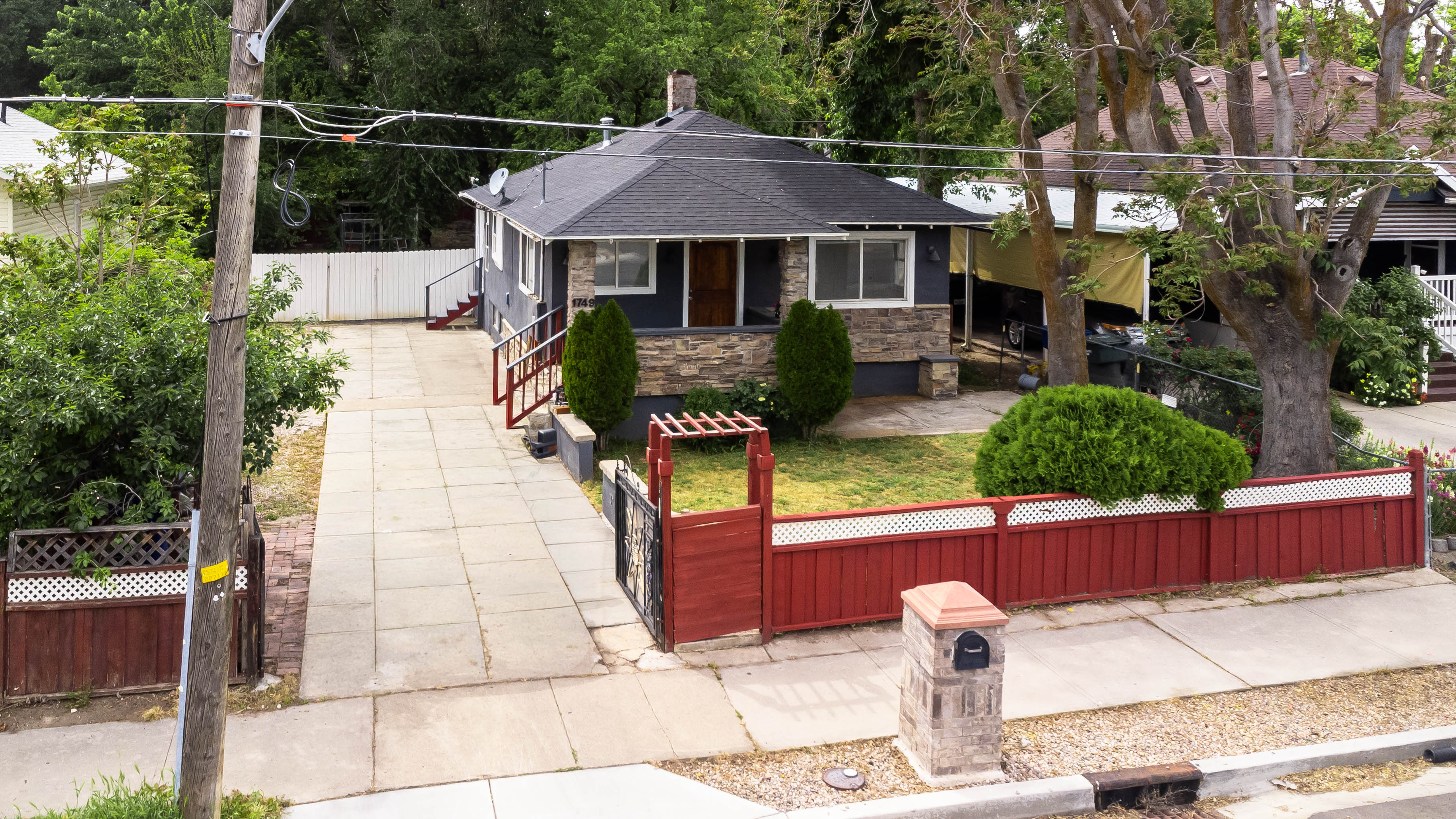 Single-story residence featuring a dark grey exterior with stone veneer accents, a dark shingled roof, and white window frames