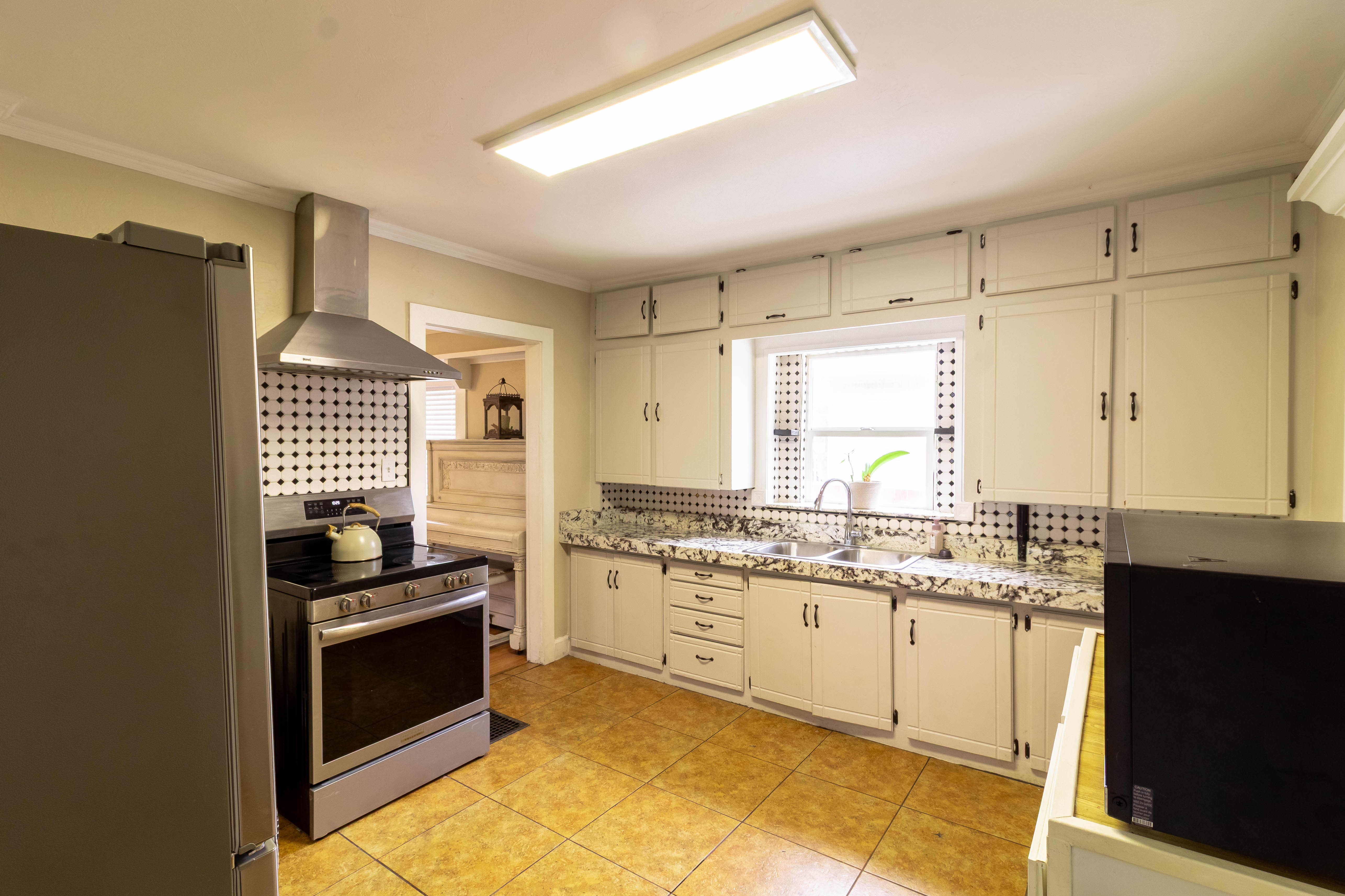 Kitchen featuring white cabinetry, patterned backsplash, granite-finish countertops, and tile flooring