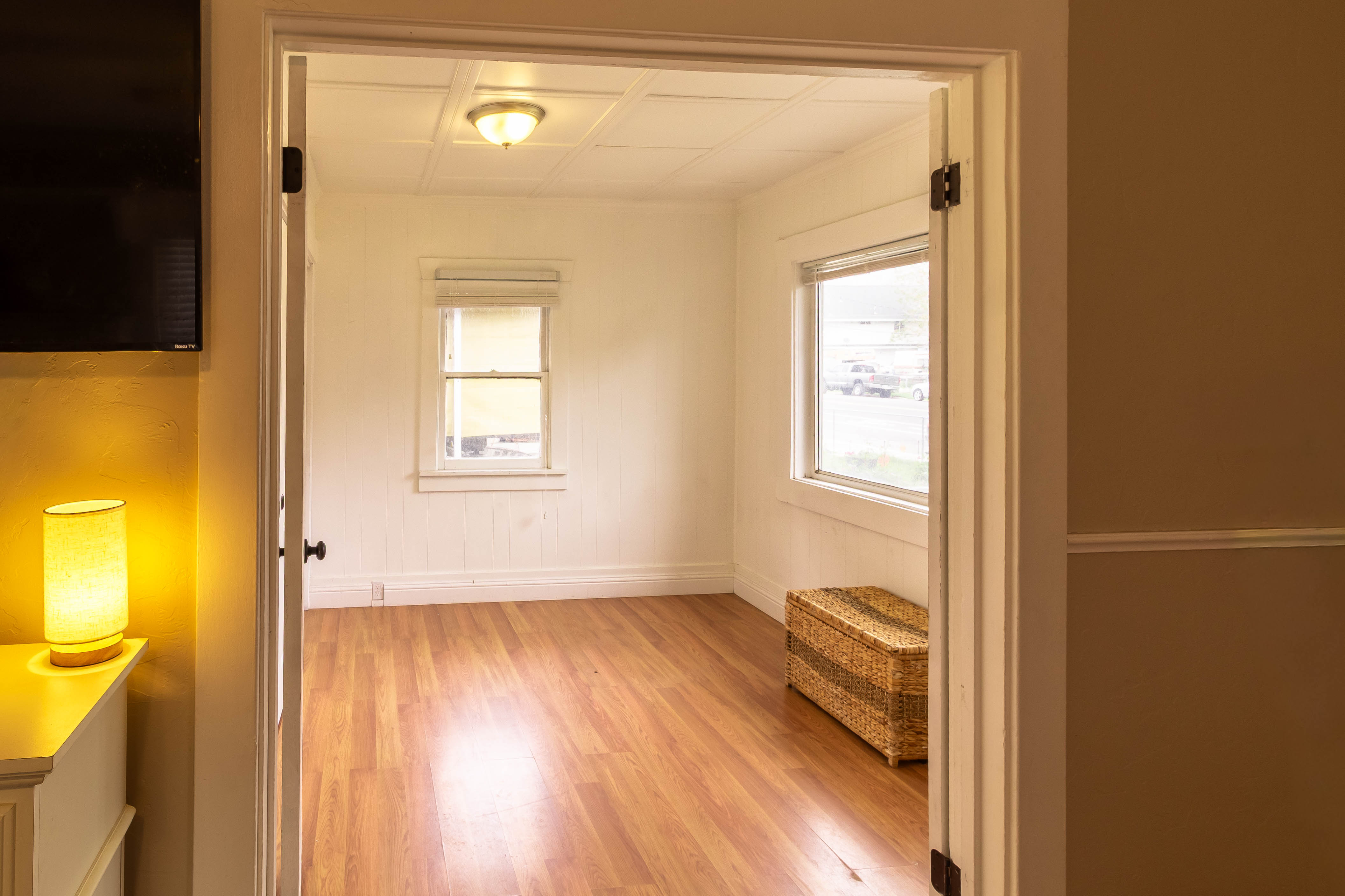 Hardwood-style flooring throughout a room with white walls, multiple windows, and a ceiling light fixture