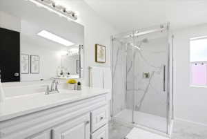 Contemporary bathroom featuring a white vanity with integrated sink, chrome faucet, and a large mirror with vanity lighting