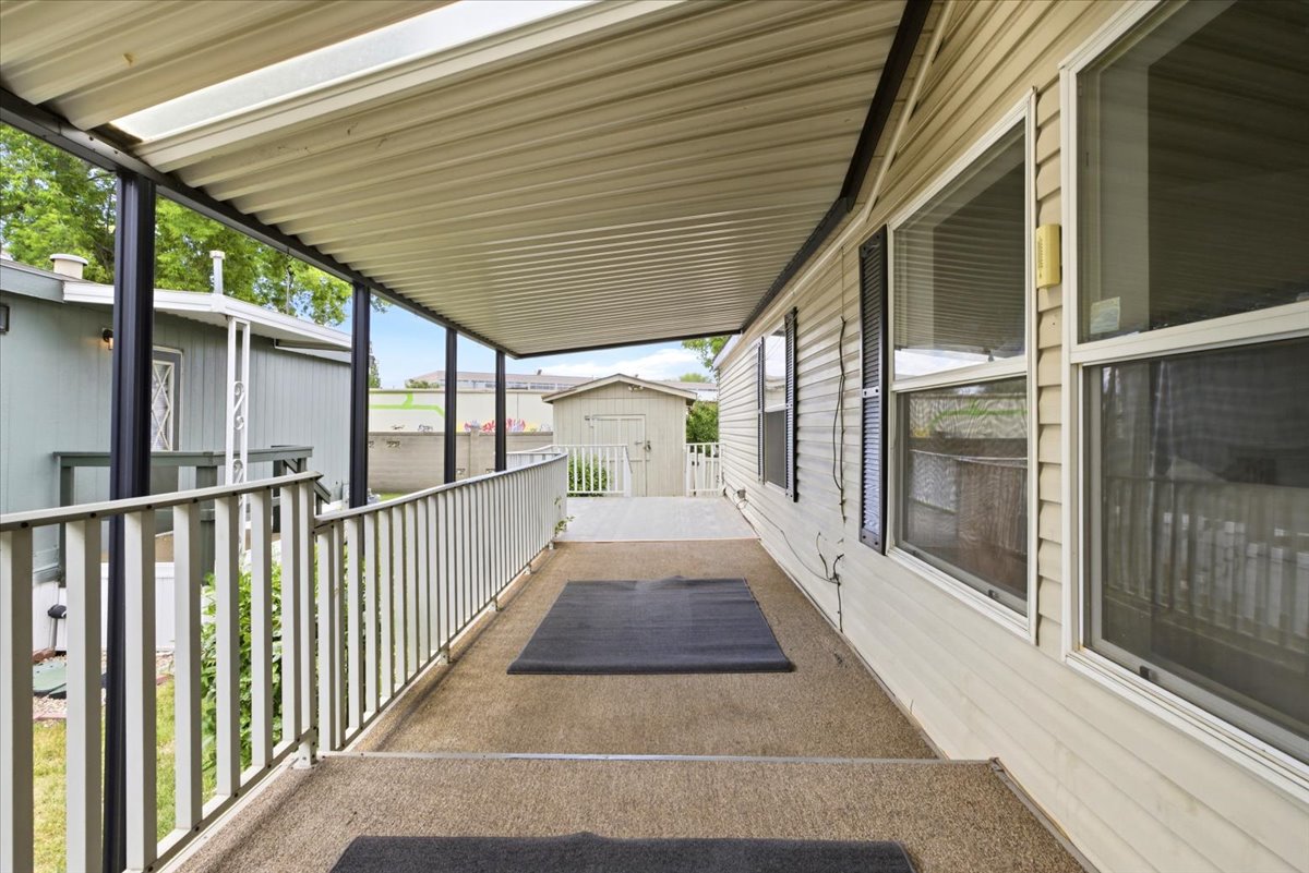 Covered porch with carpeted flooring, white railing, and exterior siding