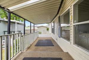 Covered porch with carpeted flooring, white railing, and exterior siding
