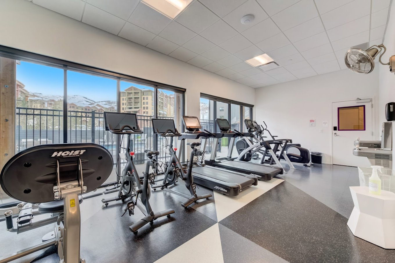 Fitness area featuring full-height glass doors, a patterned rubber floor, and a mountain backdrop