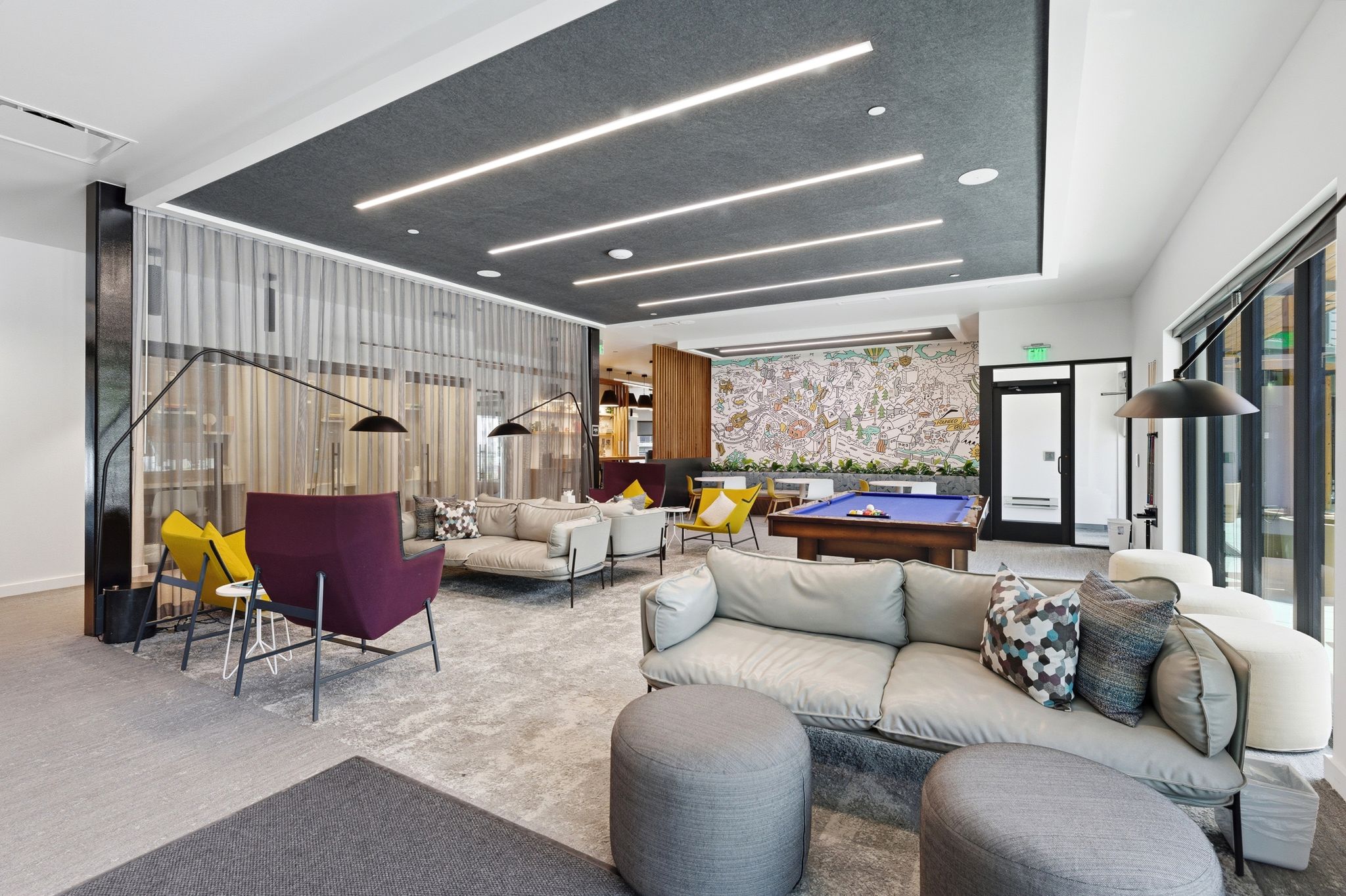 Spacious lounge area featuring a pool table, wall-mounted art, and large windows