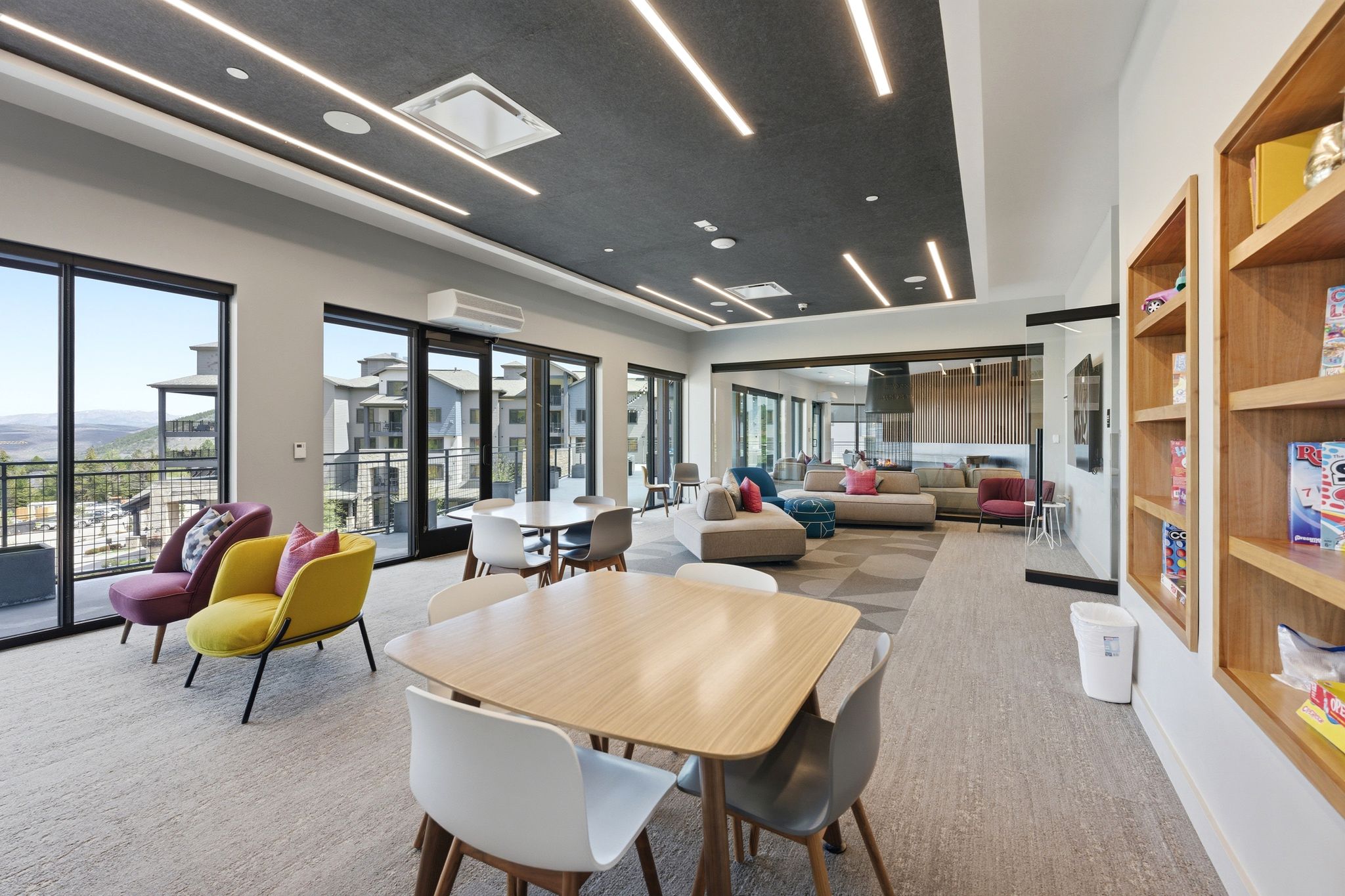 Community lounge featuring expansive windows, recessed linear lighting, built-in shelving, and direct outdoor access