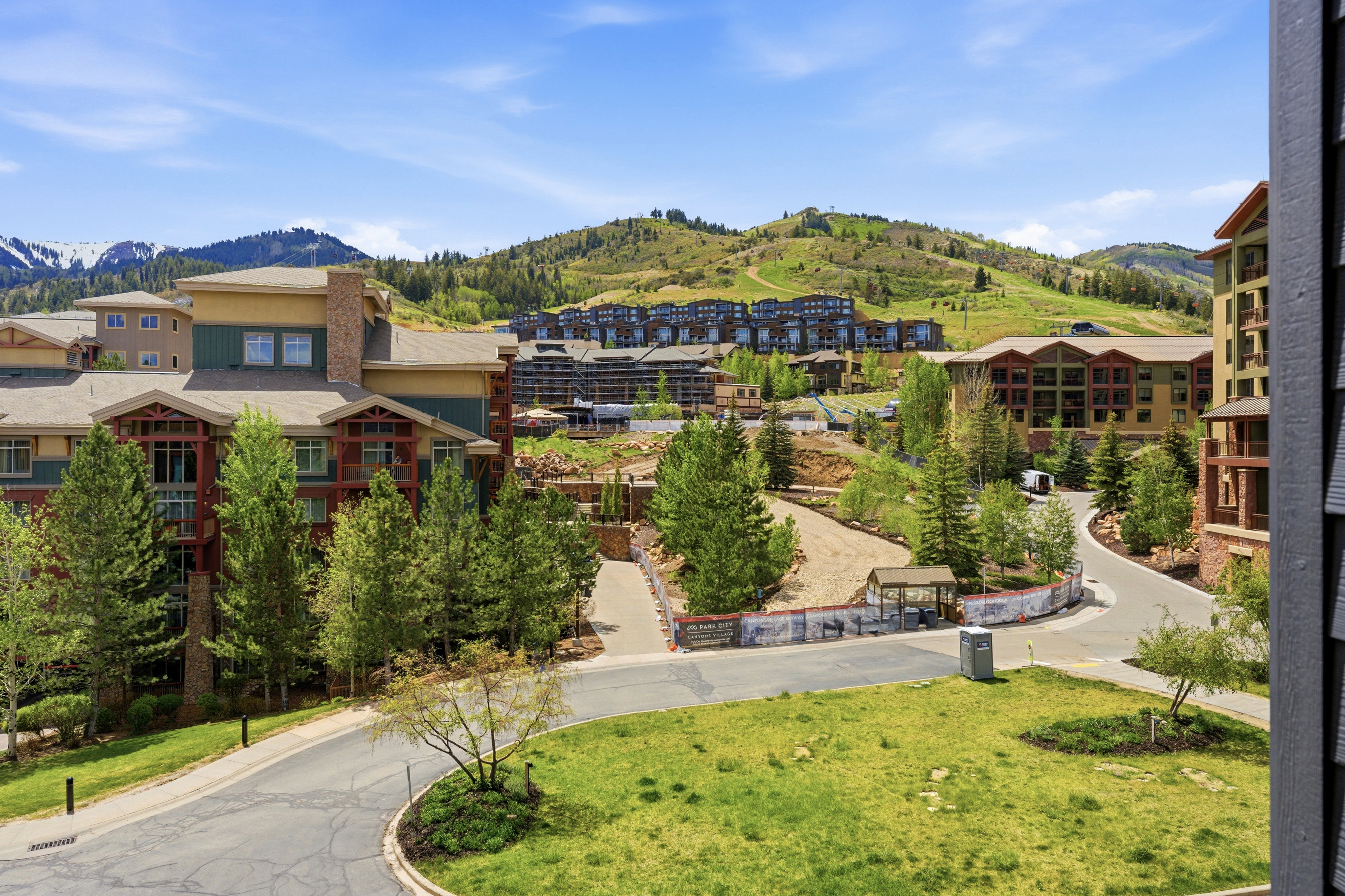 Mountainous landscape featuring multiple multi-story residential buildings, green hillsides, and paved roadways