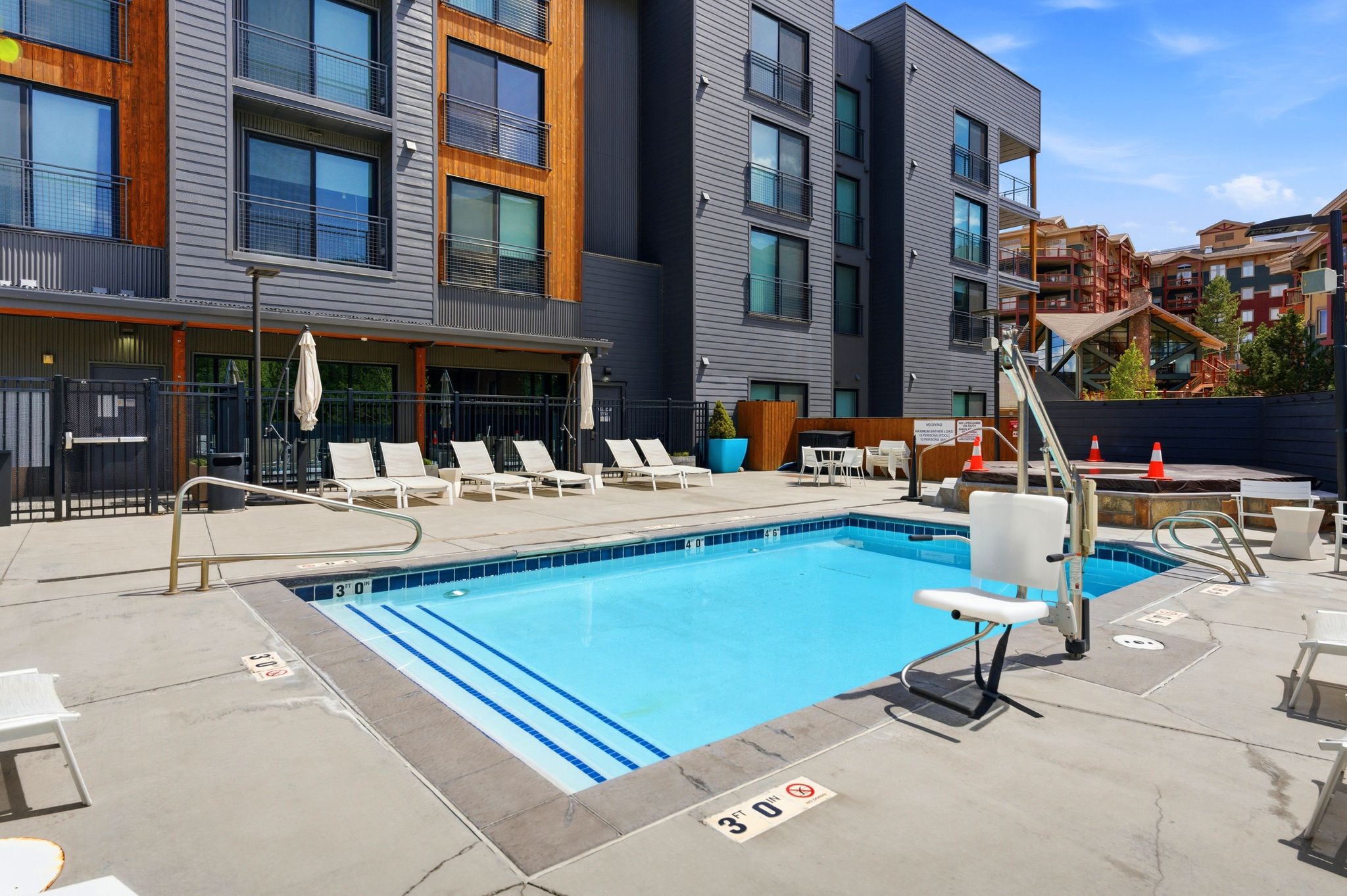 Outdoor swimming pool featuring a shallow entry with integrated steps, surrounded by a concrete deck