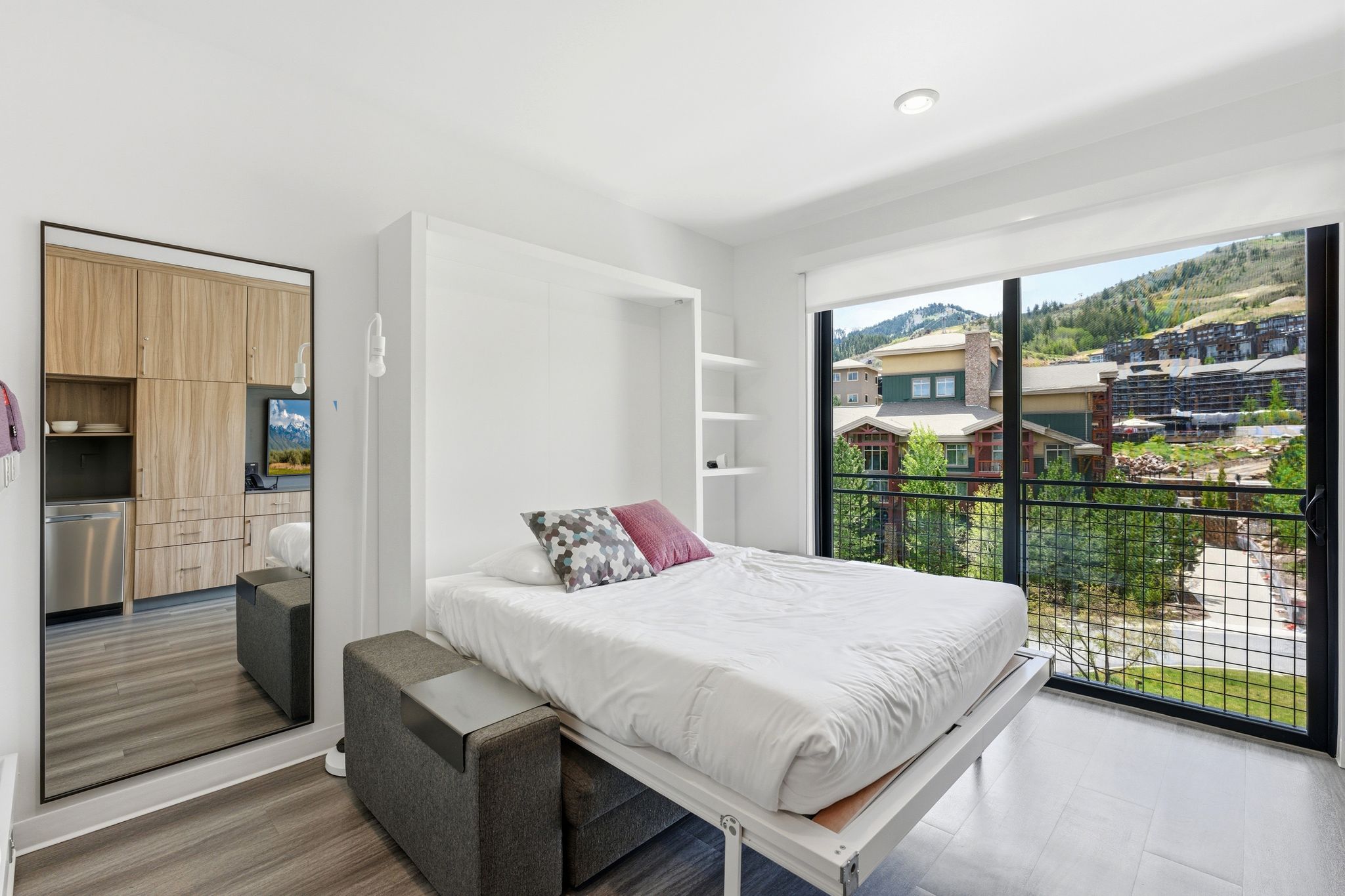 Contemporary studio space featuring a wall-mounted bed, built-in shelving, and wood-finish flooring