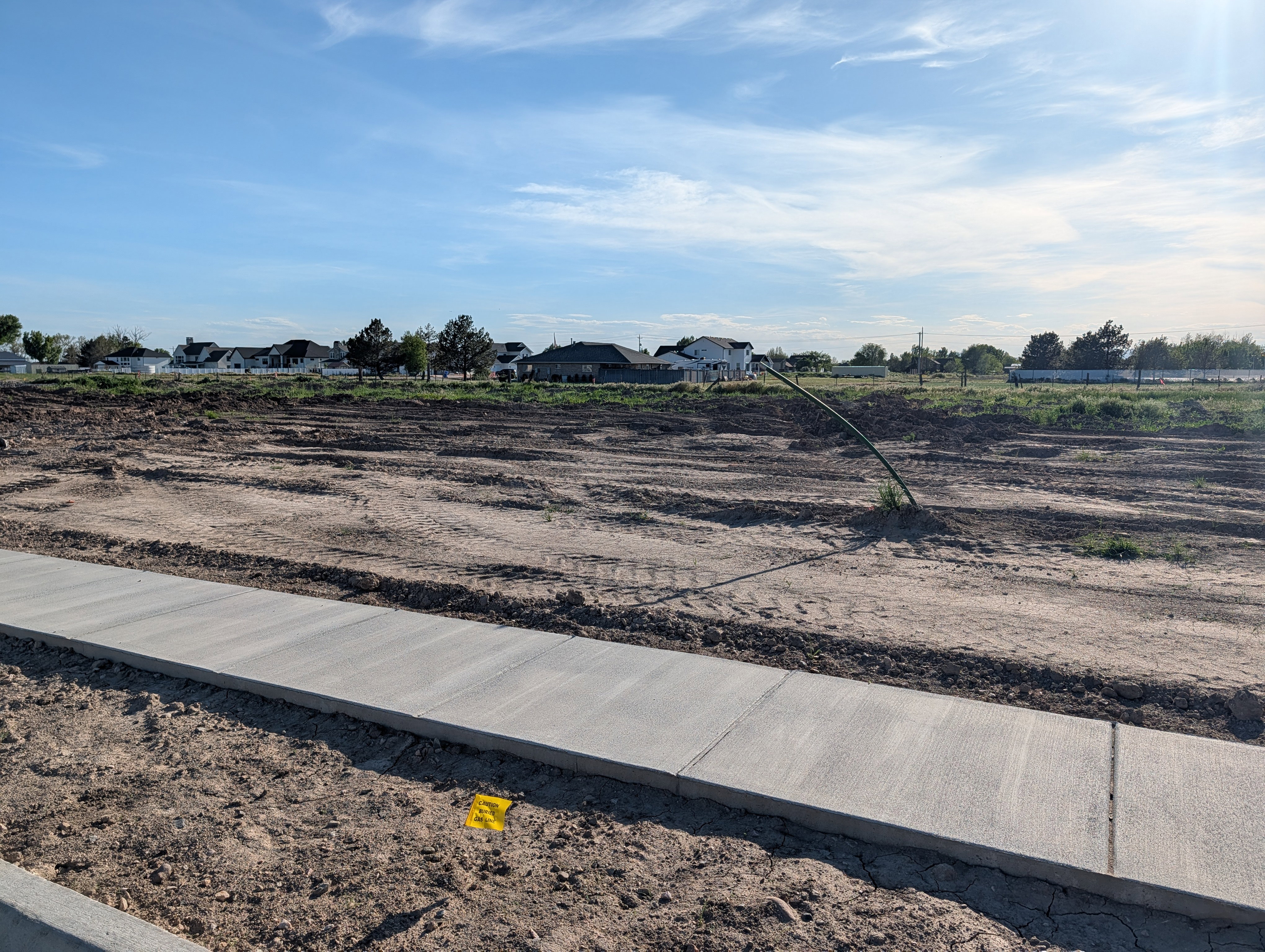 Newly poured concrete sidewalk with a dirt lot foreground