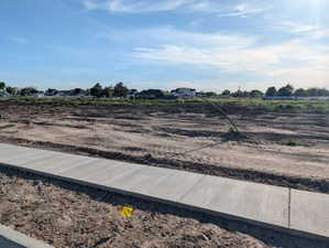 Newly poured concrete sidewalk with a dirt lot foreground