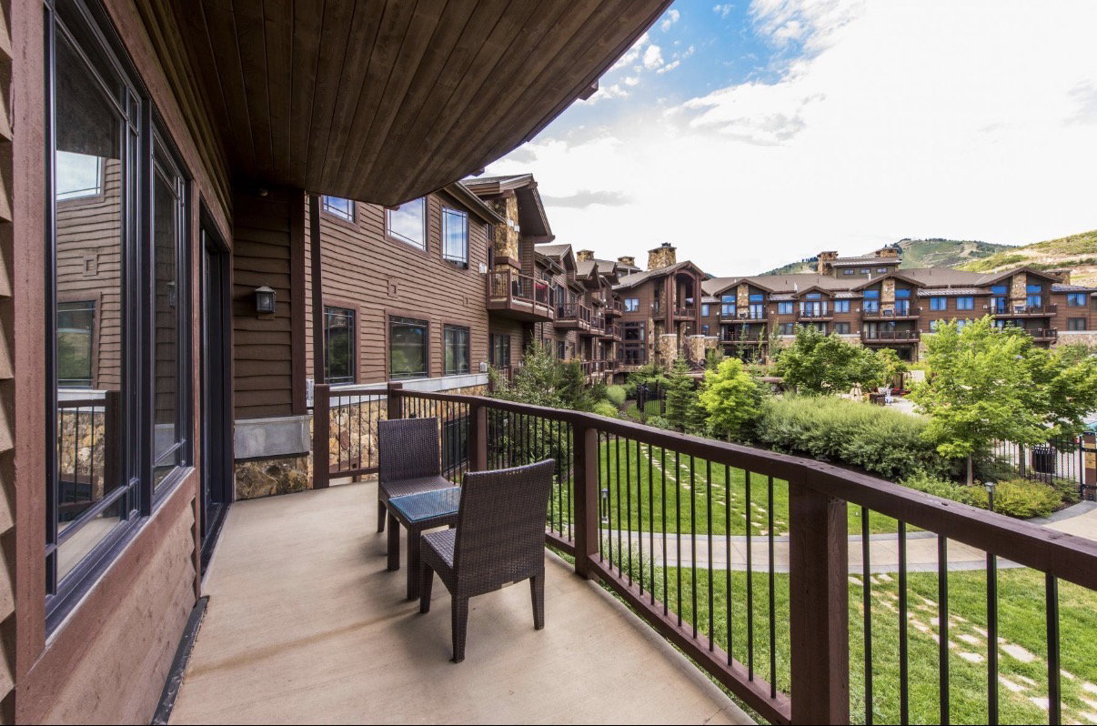Private balcony with a metal railing, overlooking a landscaped green space