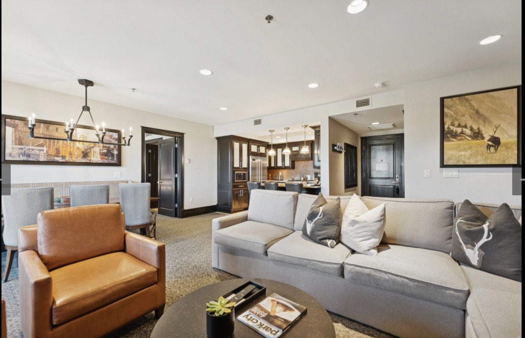 Open-concept living area featuring recessed lighting, a dining area with a linear chandelier, dark-stained trim work, and a kitchen with pendant lighting
