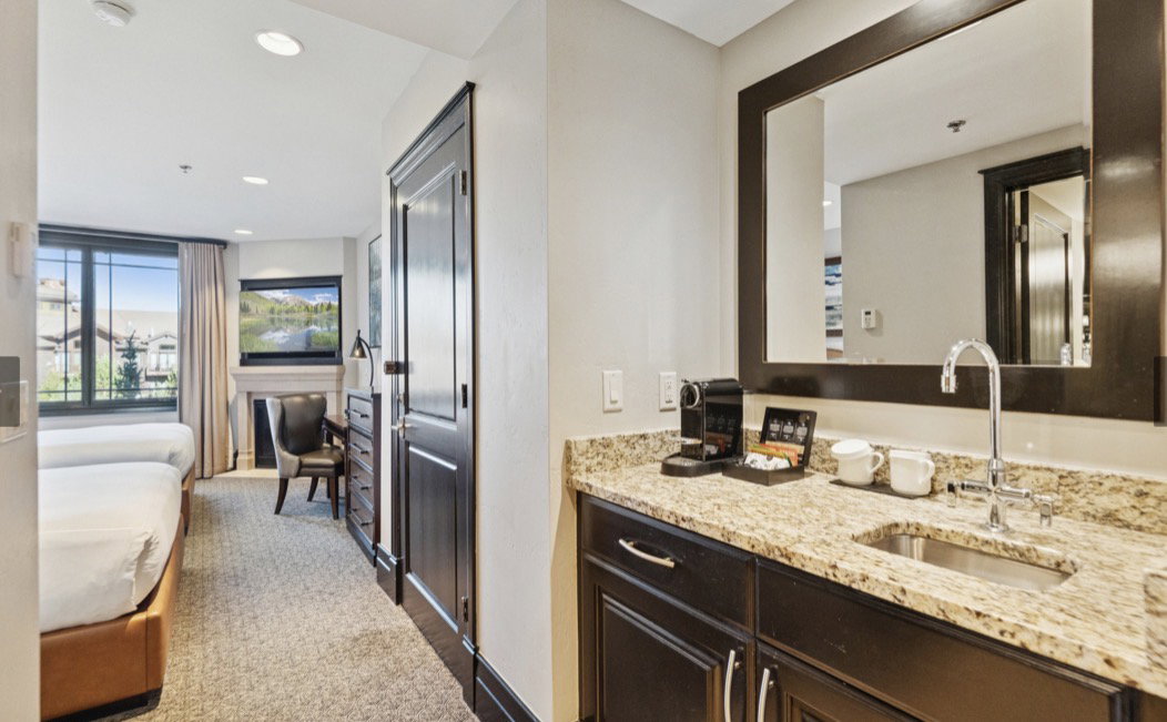 Integrated wet bar featuring a granite-look countertop, undermount stainless steel sink, and dark wood cabinetry
