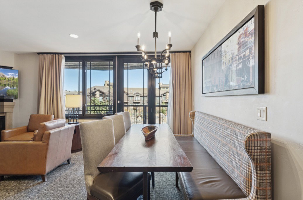 Dining area featuring a dark wood-finish table, built-in upholstered banquette seating, and a multi-bulb chandelier