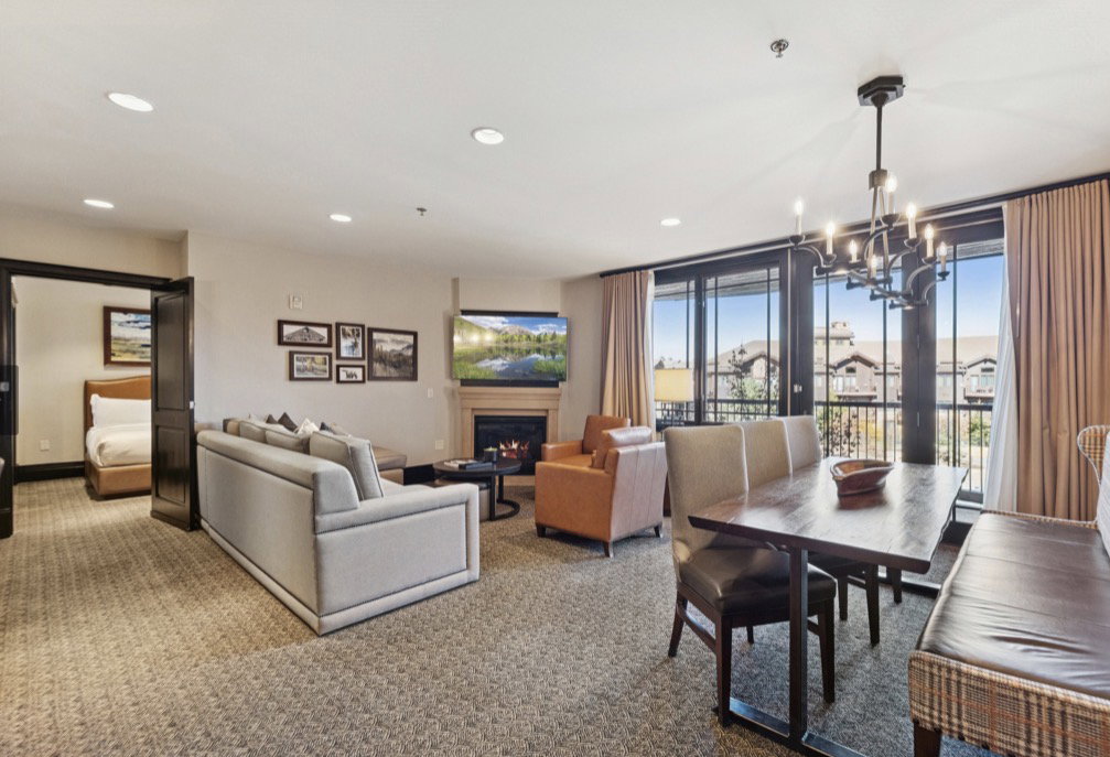 Combined living and dining area featuring a built-in fireplace, recessed lighting, and expansive glass doors opening to an exterior balcony