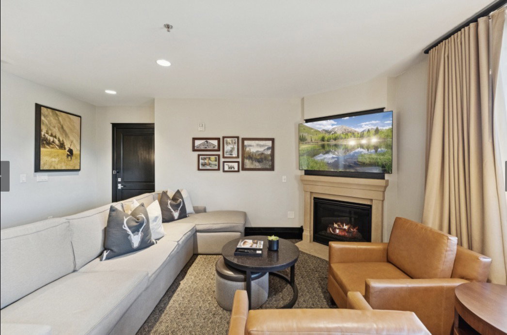 Corner fireplace with stone-finish mantel, recessed lighting, and wall-mounted television