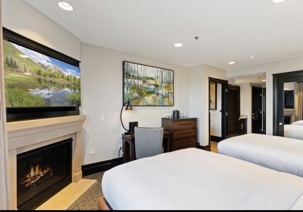 Stone fireplace with a mounted television above, recessed lighting, and dark trim details