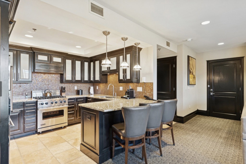 Gourmet kitchen featuring dark wood cabinetry with glass-front uppers, a mosaic tile backsplash, and granite countertops
