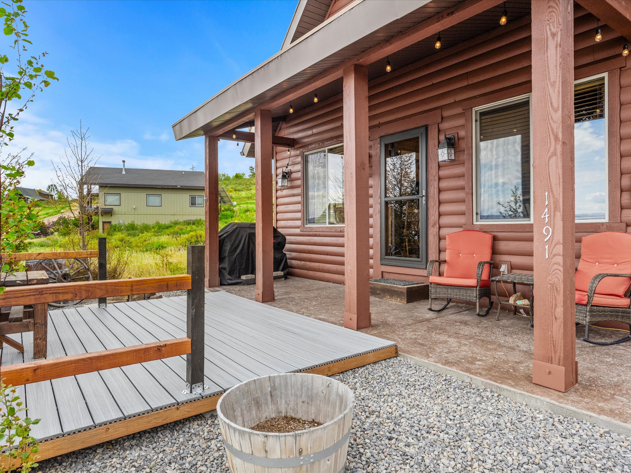 Log-style exterior featuring a covered porch, string lighting, and a composite deck with wooden railings