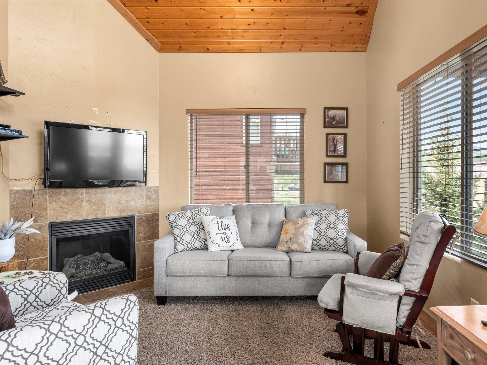 Living area featuring a textured vaulted ceiling, a gas fireplace with a stone surround, and light-colored walls