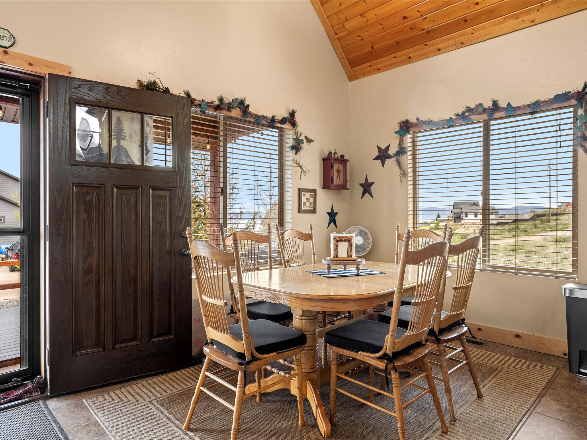 Vaulted wood-paneled ceiling above a dining area featuring large windows with horizontal blinds