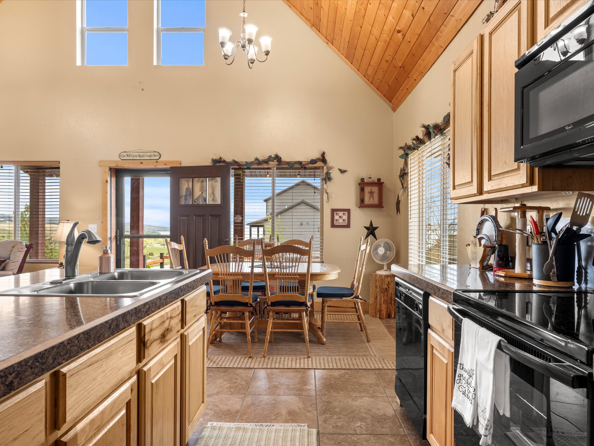 Kitchen featuring warm wood-finish cabinetry, black appliances, and a double basin stainless steel sink