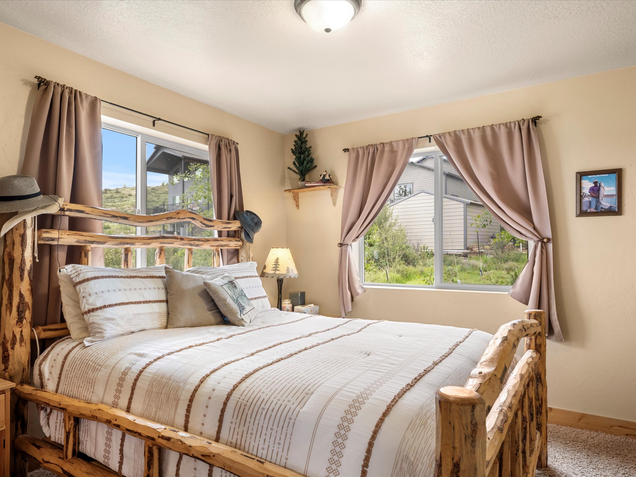 Carpeted bedroom featuring two windows with natural light, a ceiling-mounted light fixture, and neutral wall paint