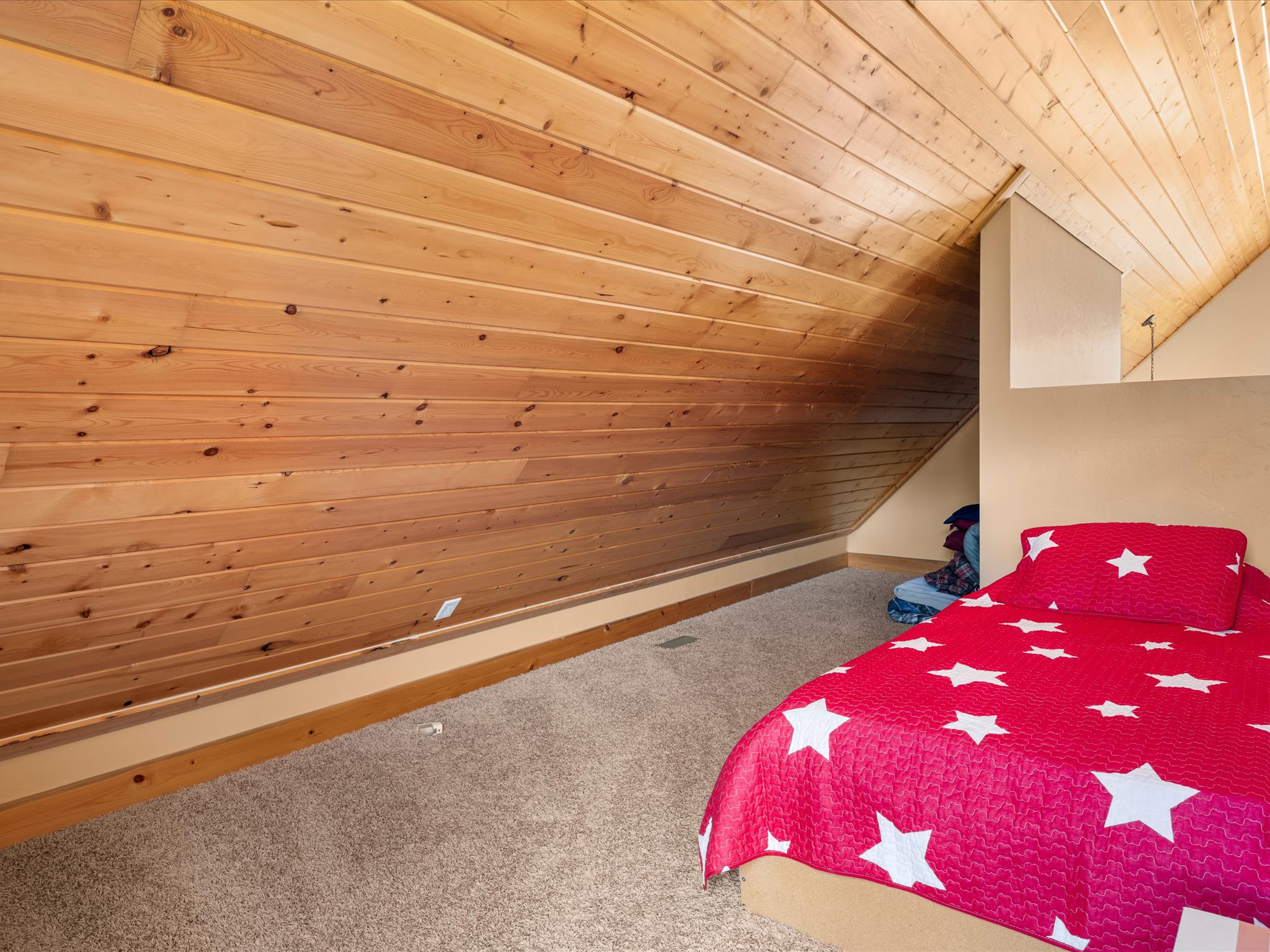 Room featuring sloped wood-paneled walls, a matching wood-paneled ceiling, and light brown carpeting