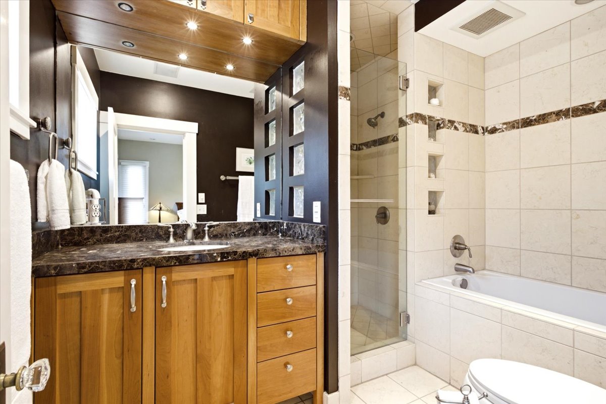 Bathroom featuring a single vanity with wood cabinetry, a dark stone countertop, and an undermount sink