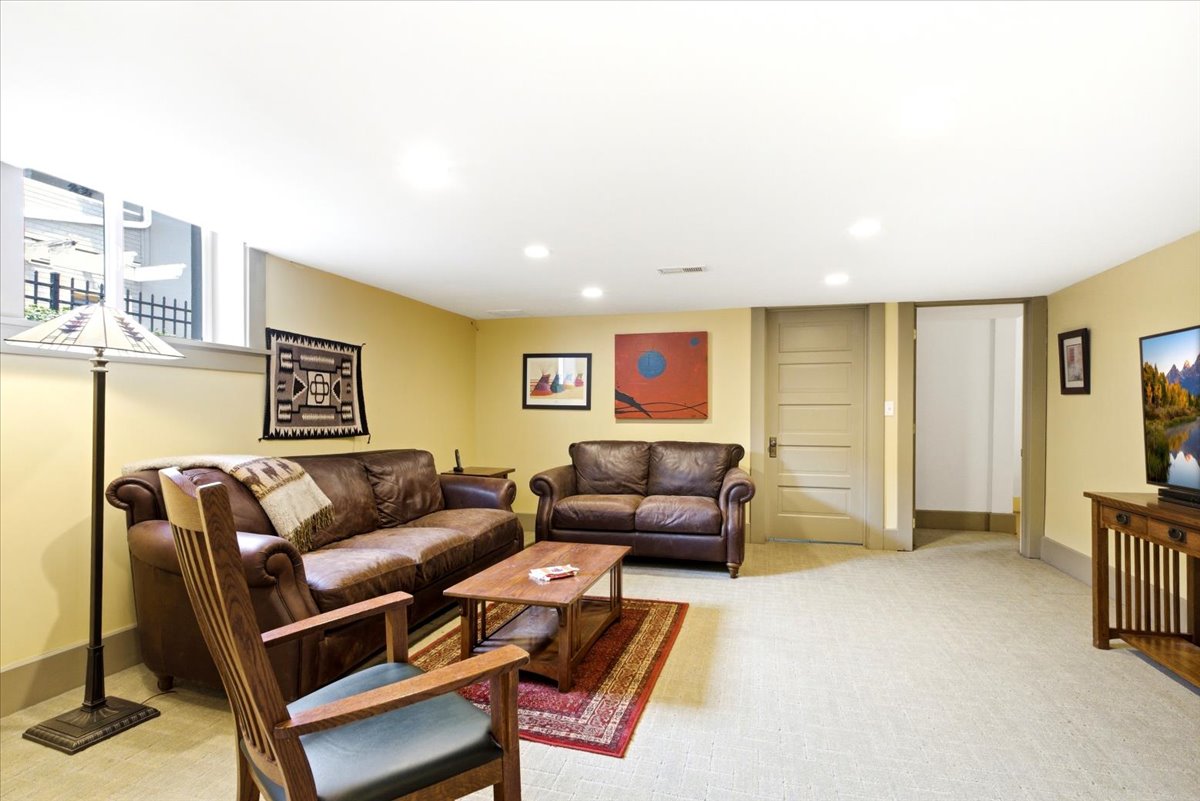 Spacious room featuring light-colored carpet flooring, recessed lighting, and a window with security bars