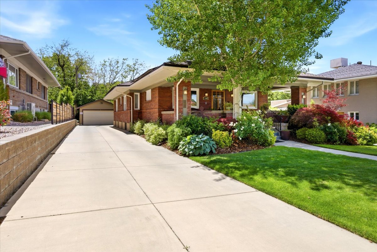 Brick exterior home featuring a well-maintained lawn, mature trees, and extensive landscaping