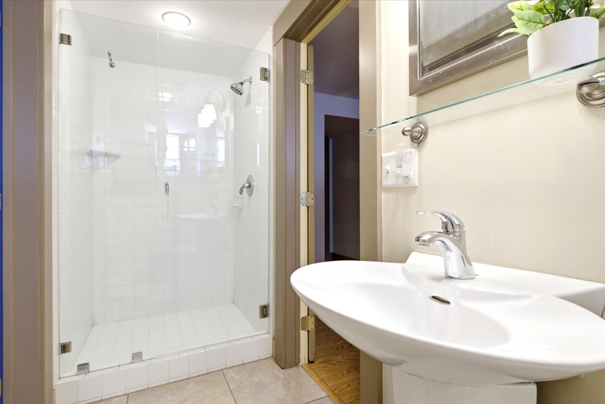 Contemporary bathroom featuring a glass-enclosed shower with white subway tile, dual shower heads, and chrome fixtures