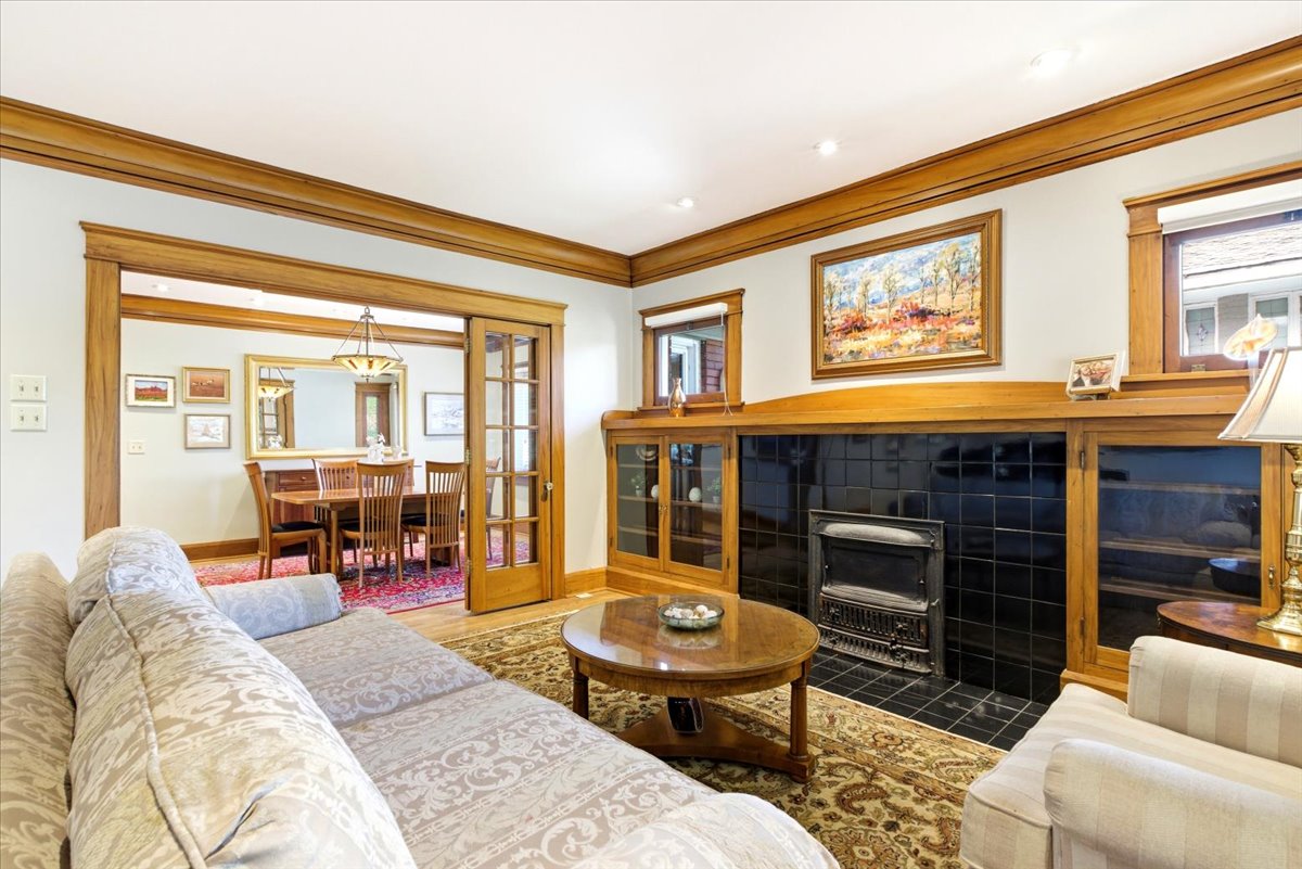 Living room featuring rich wood trim, a tiled fireplace, and built-in cabinetry