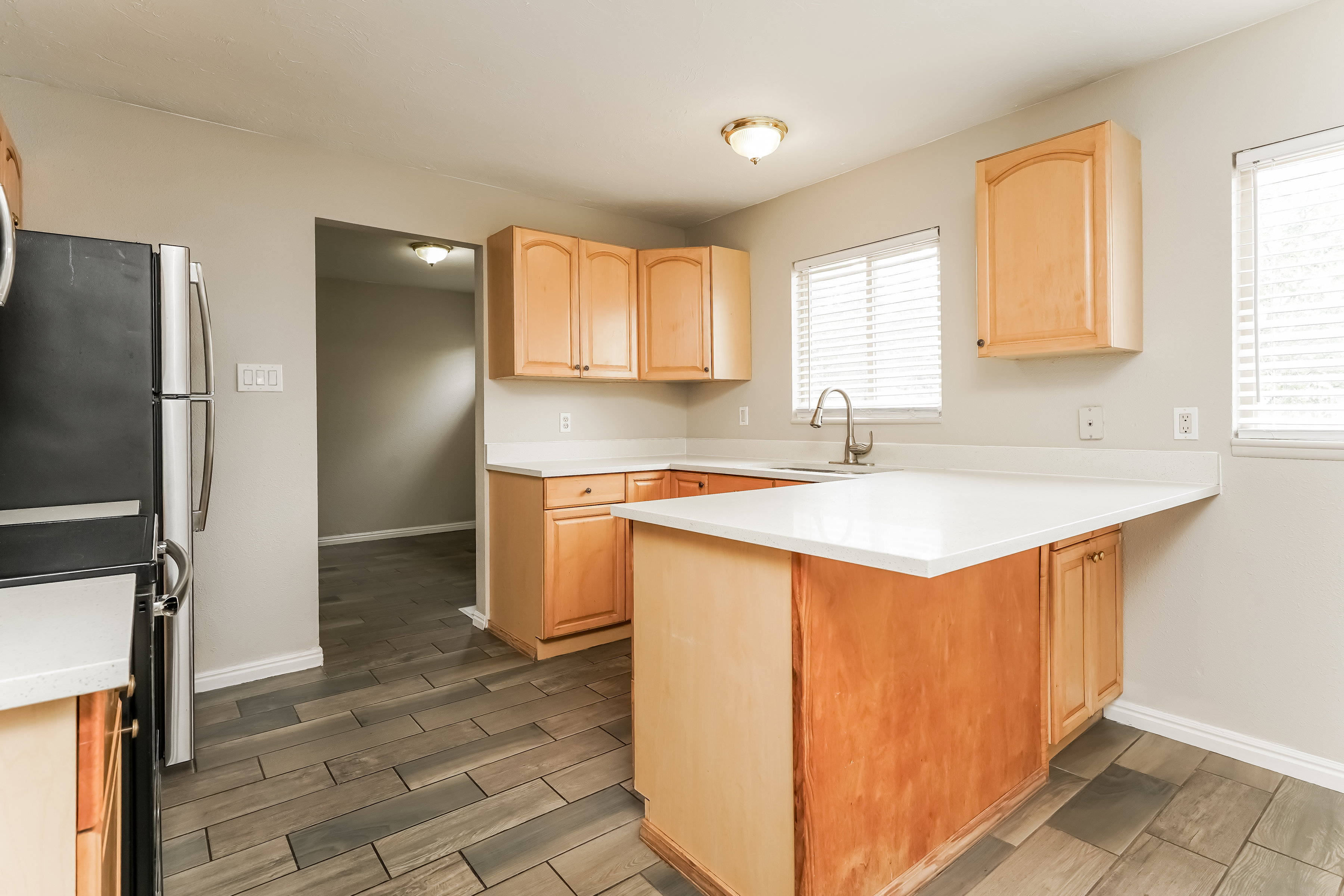 Kitchen featuring light wood cabinetry, white countertops, stainless steel sink with a gooseneck faucet, a built-in kitchen island, and wood-finish flooring